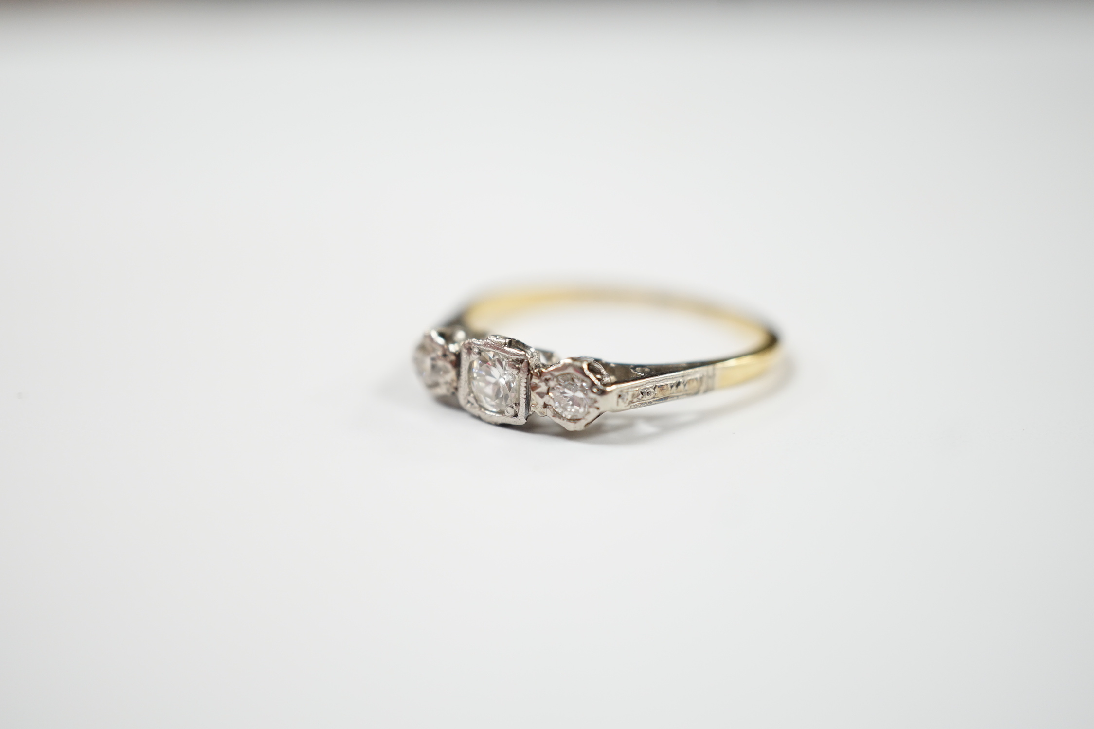 An 18ct, plat and three stone diamond set ring, size N/O, gross weight 2.1 grams.